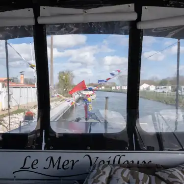 Vue depuis un bateau Le Mer Veilleux du port de plaisance d'Aire-sur-la-Lys avec drapeaux colorés et bâtiments
