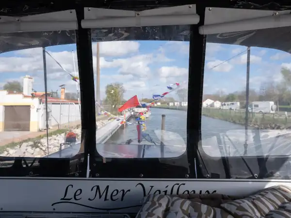 Vue depuis un bateau Le Mer Veilleux du port de plaisance d'Aire-sur-la-Lys avec drapeaux colorés et bâtiments