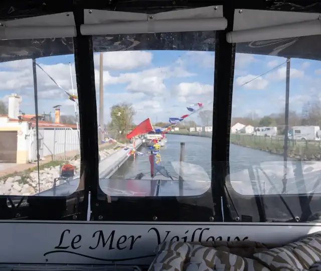 Vue depuis un bateau Le Mer Veilleux du port de plaisance d'Aire-sur-la-Lys avec drapeaux colorés et bâtiments